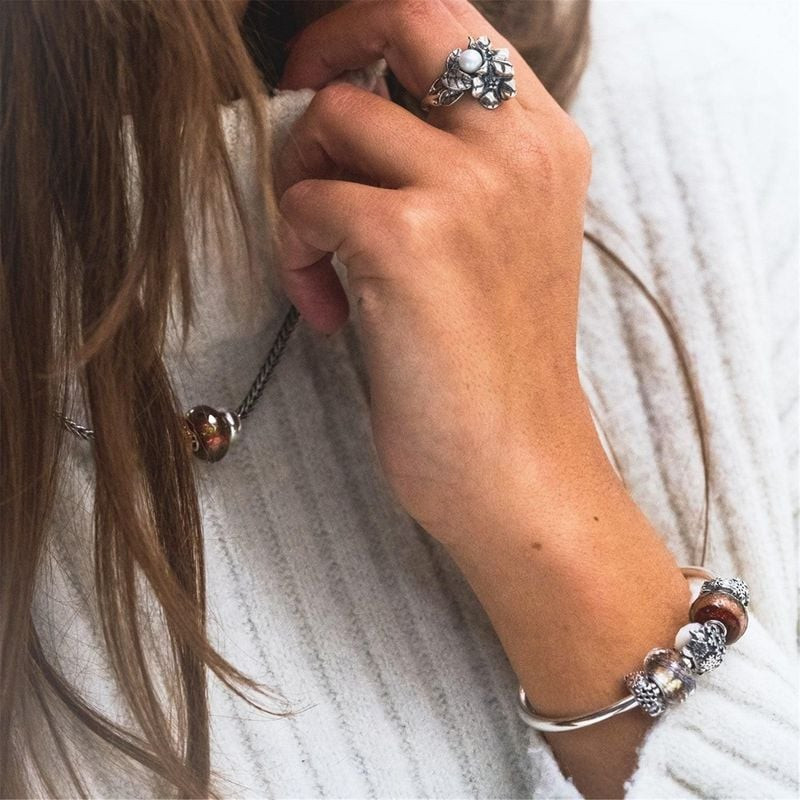 Femme portant la perle en verre Trollbeads Vœux Chaleureux sur un collier en argent et un bracelet à