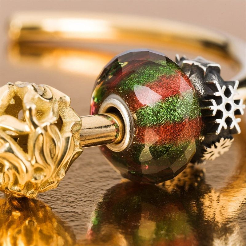 Perle de Noël Trollbeads en verre avec breloques flocon de neige en or et argent sur fond doré
