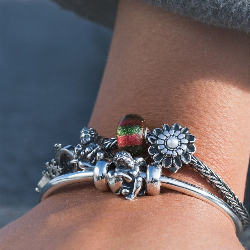 Breloque de Noël Trollbeads en verre mise en scène sur bracelet argent avec breloques ange et fleur