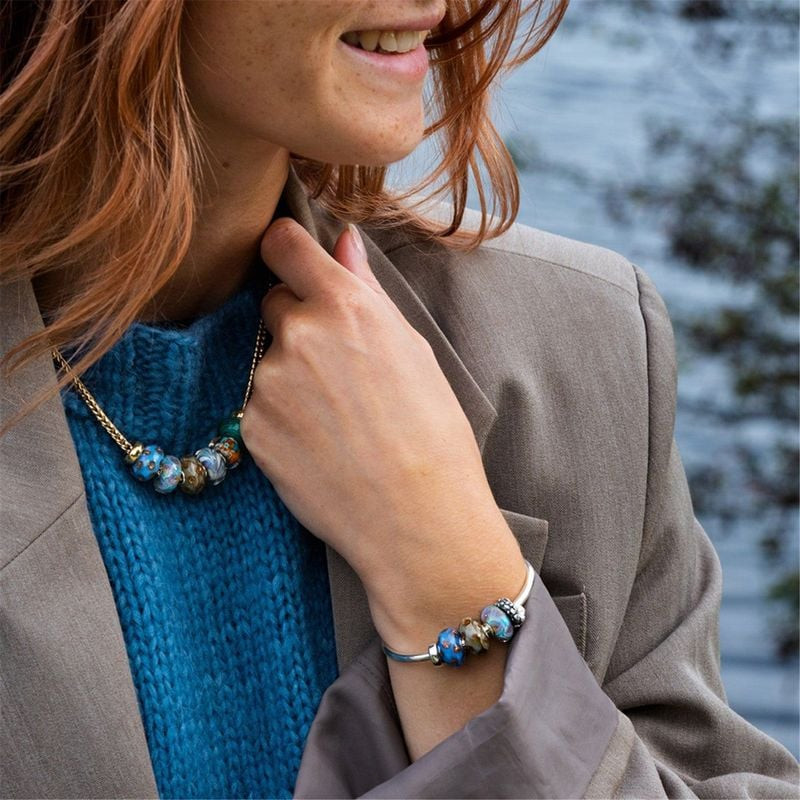 Perle Trollbeads Rivière d'Or Verre Bleu portée sur un bracelet, éclats dorés et bleus.
