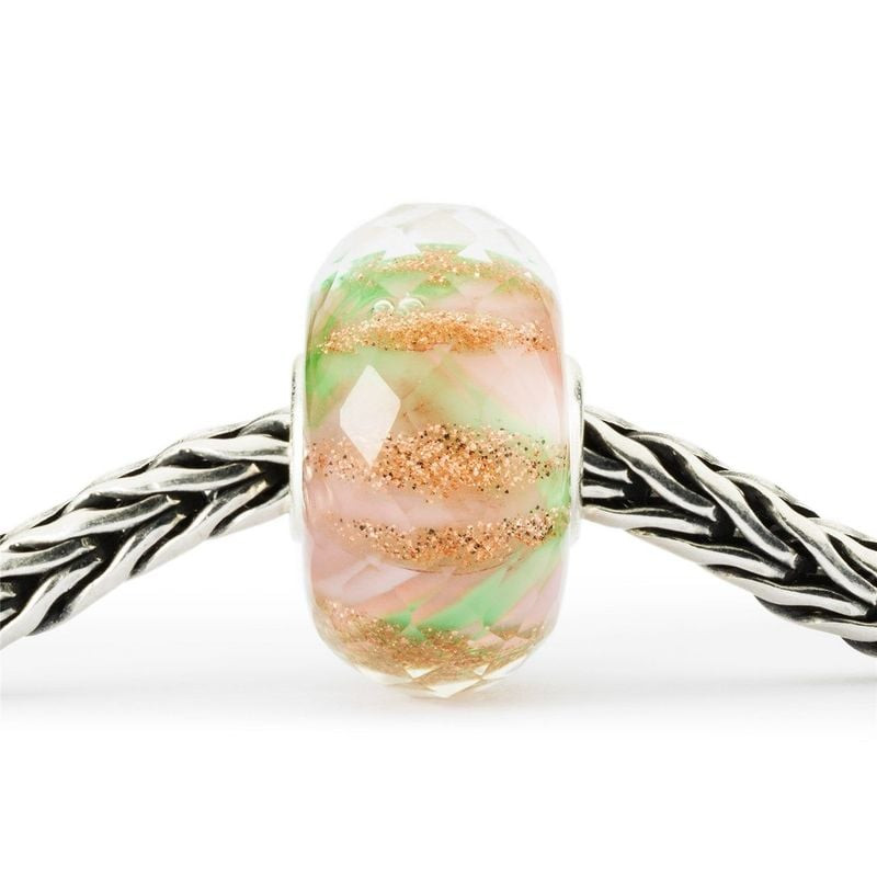 Perle en verre TROLLBEADS LIT DE FLEURS avec paillettes roses, vertes et dorées sur un bracelet en a