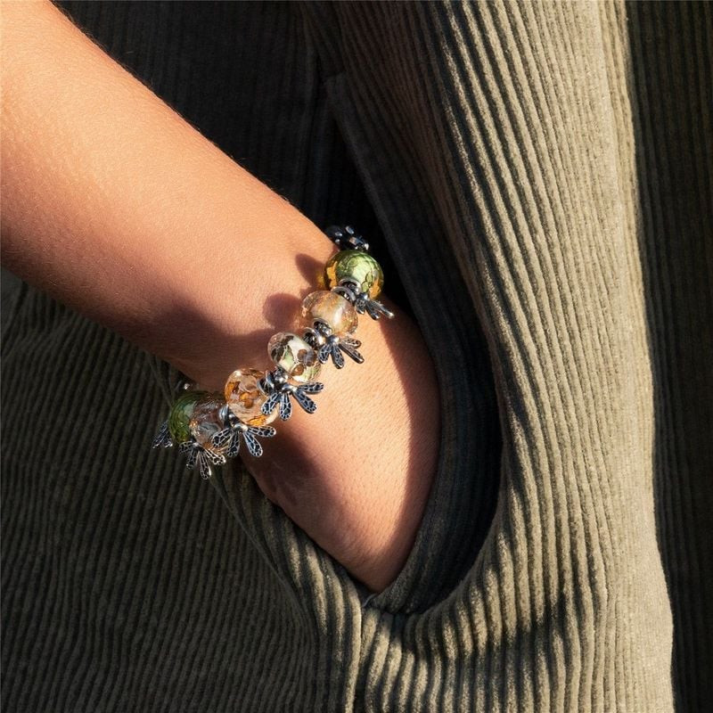 Gros plan sur un poignet portant un bracelet Trollbeads avec la perle Lit de Fleurs et des charms ab
