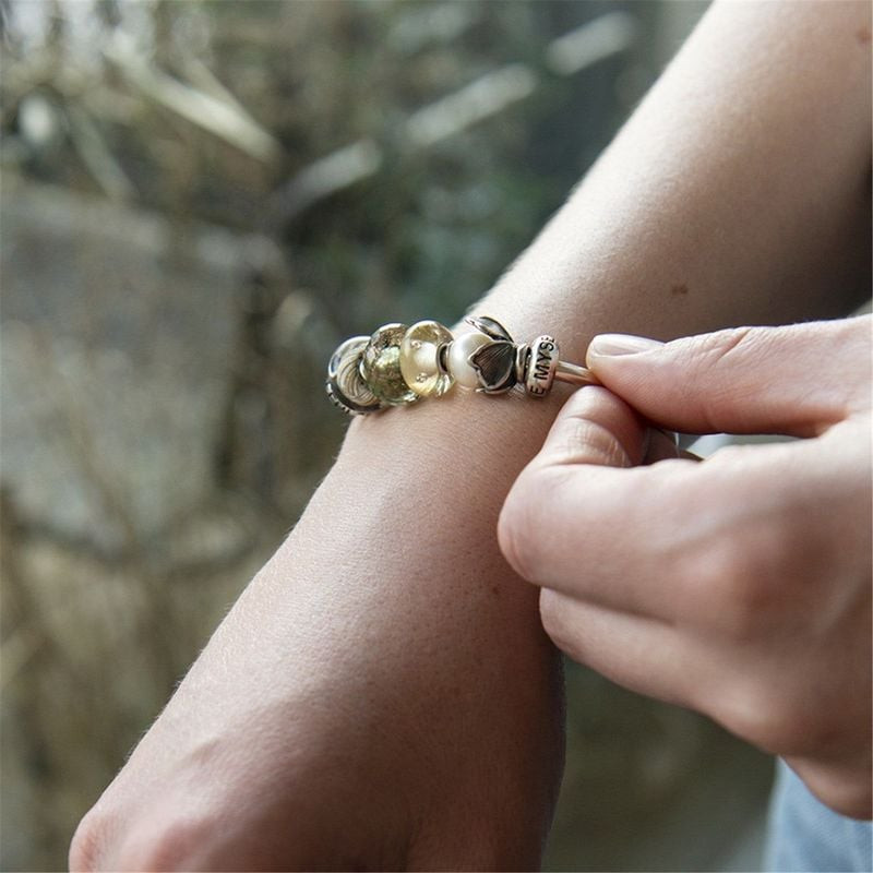 Perle Trollbeads Carefree Facettée Verre Vert Doré portée sur un bracelet, éclatante et unique.