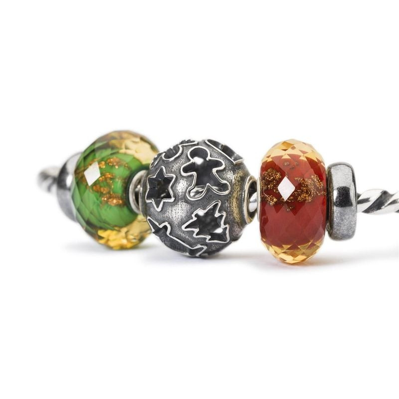 Gros plan de charms Trollbeads Scintillement rouge, verts et étoile argentée sur un bracelet
