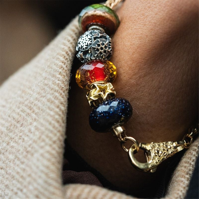 Charms en verre rouge et bleu TROLLBEADS Scintillement rouge portés au poignet sur un pull en maille