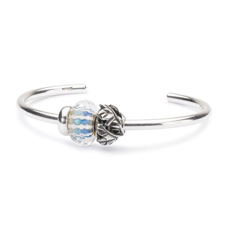 Perle en verre Trollbeads Ciel Dégagé sur un bracelet en argent massif, à côté d'une perle fleur en 