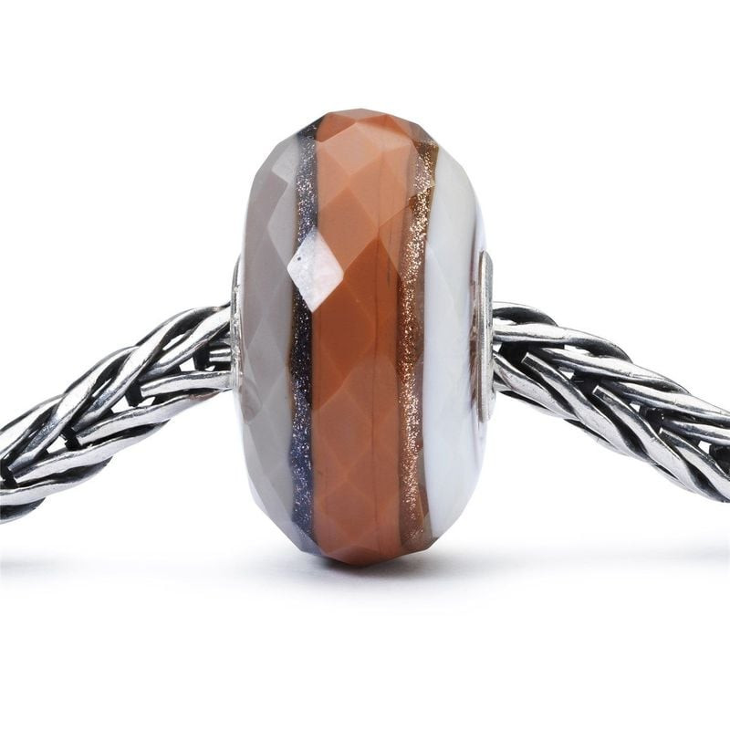 Perle Trollbeads Forest Glam Facettée Verre Multicolore posée dans un décor automnal, reflets multic