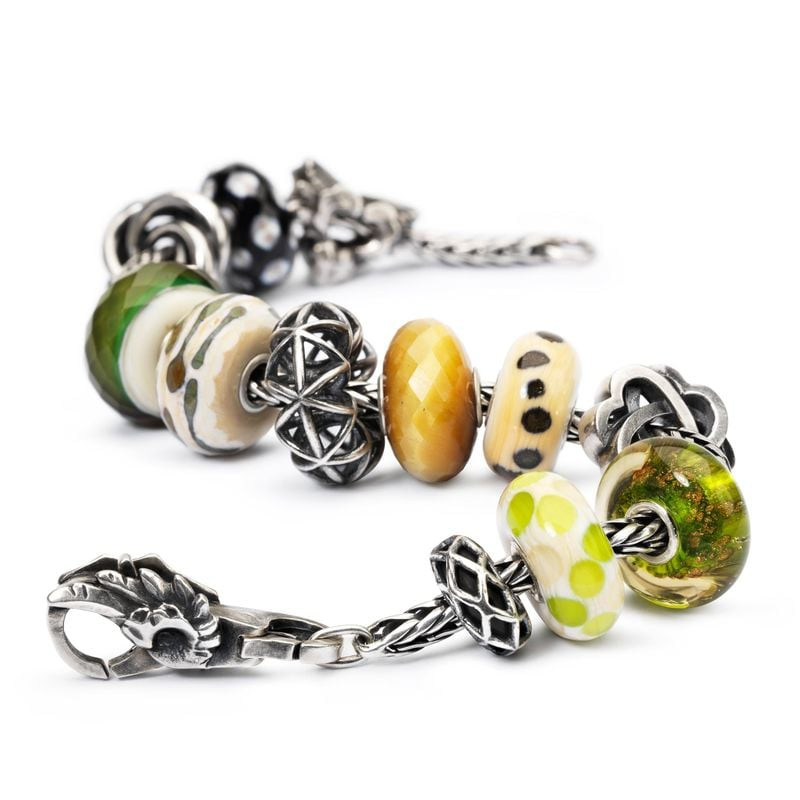 Perle de verre Trollbeads Rameaux de Saule avec des charms verts, ambrés et argentés sur un bracelet