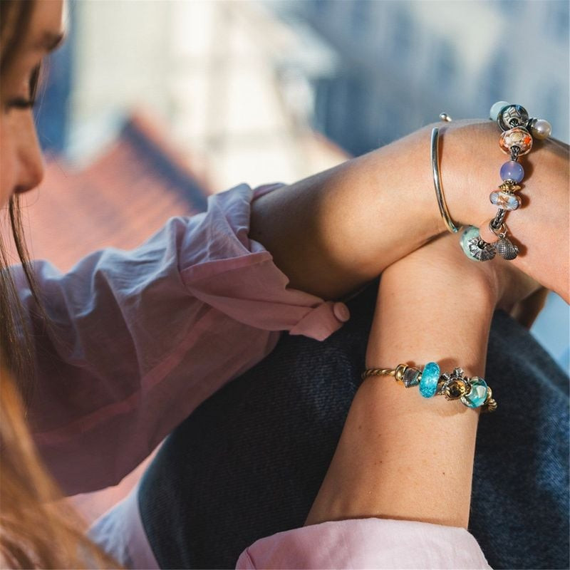 Femme portant des bracelets Trollbeads superposés avec la perle en verre Guidé par les Vagues, en in