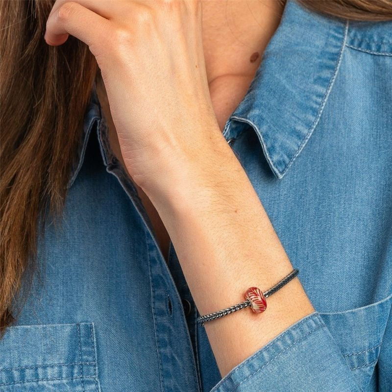 Poignet d'une femme portant un bracelet en argent Trollbeads avec la perle Winged Unity, fond de che