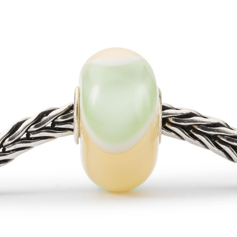 Perle en verre Trollbeads Paradis du Tatou jaune et vert pastel avec spirale blanche, enfilée sur un