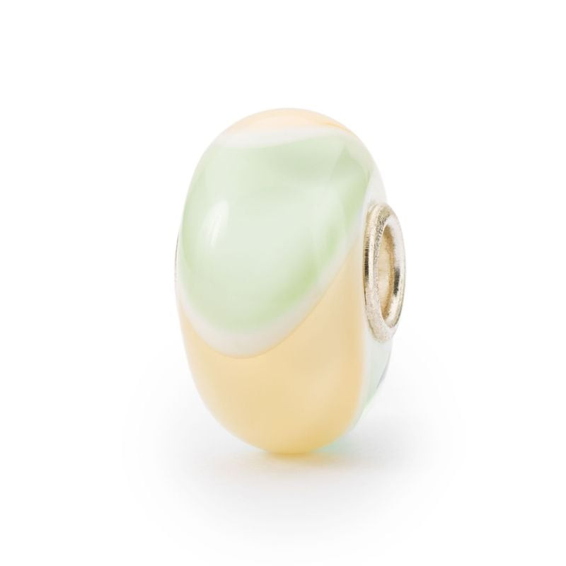 Vue inclinée de la perle Trollbeads Paradis du Tatou, verre pastel jaune et vert, ligne blanche et c