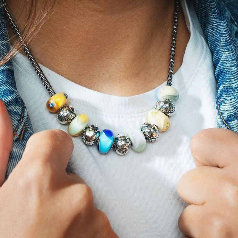 Personne portant un collier Trollbeads avec la perle Paradis du Tatou en ivoire et des perles en ver