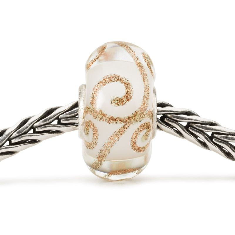 Perle en verre Trollbeads Innocence à tourbillons dorés enfilée sur un bracelet chaîne Trollbeads en