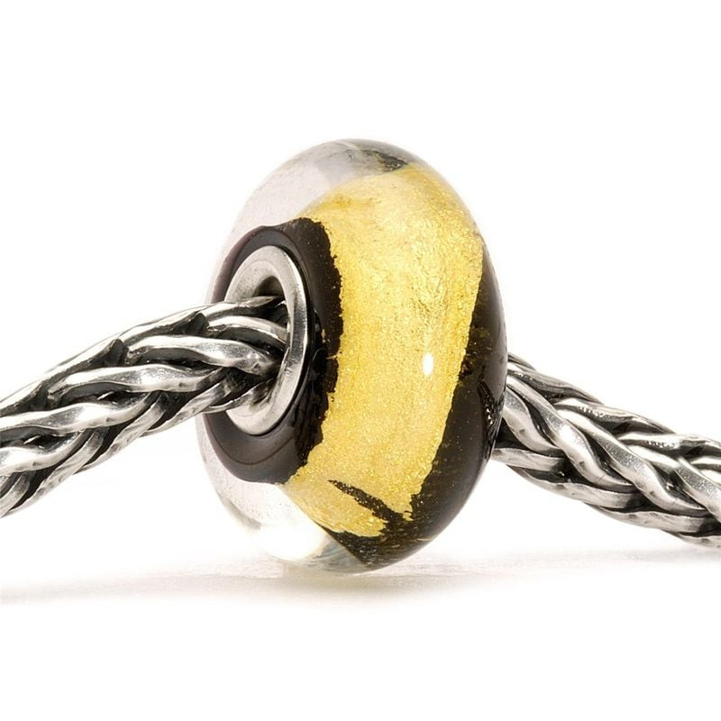 Breloque Trollbeads Or noir en verre noir enfilée sur une chaîne argent tressée, dévoilant sa bande 