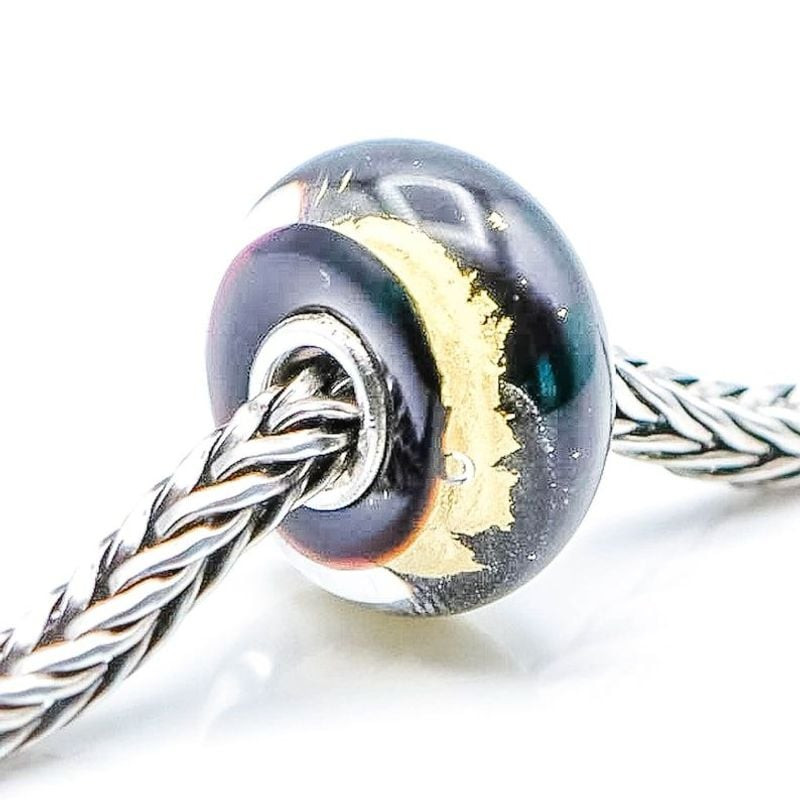 Vue inclinée de la breloque Trollbeads Or noir sur chaîne tressée, verre noir brillant avec couche d