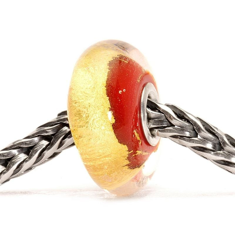 Vue inclinée de la bille Trollbeads Chakra Racine sur un bracelet en argent mettant en valeur la feu