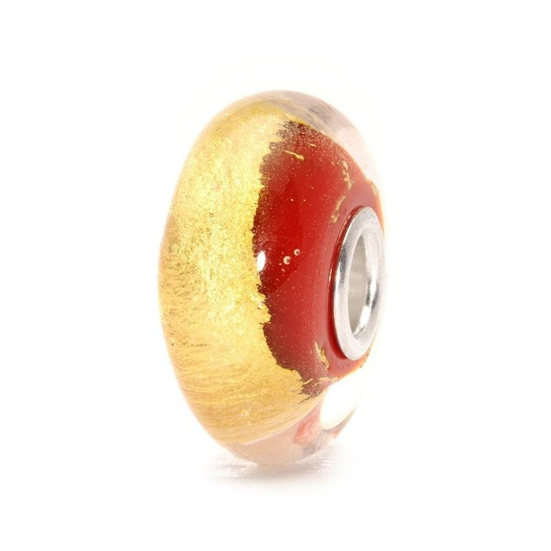 Vue de profil de la bille Trollbeads Chakra Racine, texture en feuille d'or et volutes de verre roug
