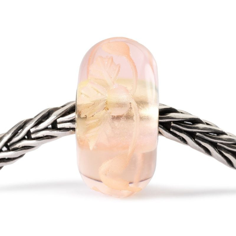 Perle en verre Trollbeads Romance gravée avec des gravures florales sur un bracelet en argent.