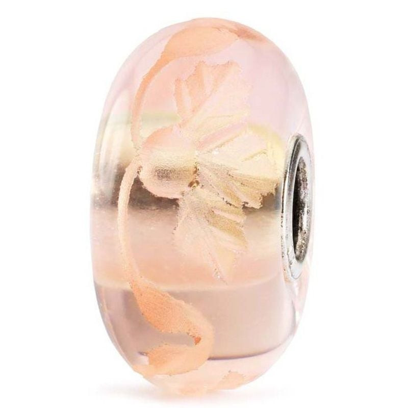 Gros plan sur la perle en verre Trollbeads Romance gravée, mettant en valeur ses gravures florales c