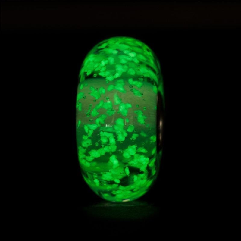 Gros plan sur la perle en verre Trollbeads Lueur intérieure qui brille d'un vert vif dans l'obscurit