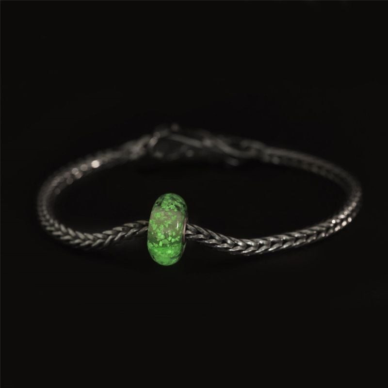 Breloque Trollbeads Lueur intérieure brillante en vert vif sur un bracelet en argent sur fond noir