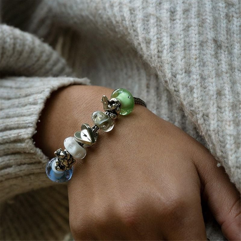 Bracelet Trollbeads au poignet d'une femme avec la perle en verre Drops of White et des charms verts