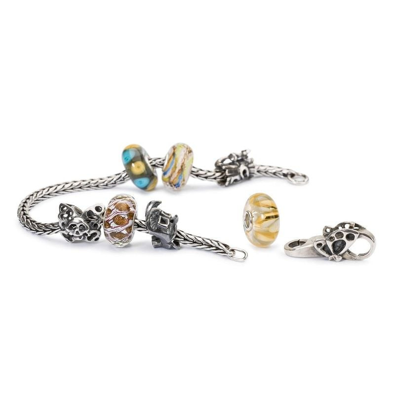 Collection de bracelets Trollbeads avec la perle de verre Brise chaude exposée à côté de charms en a