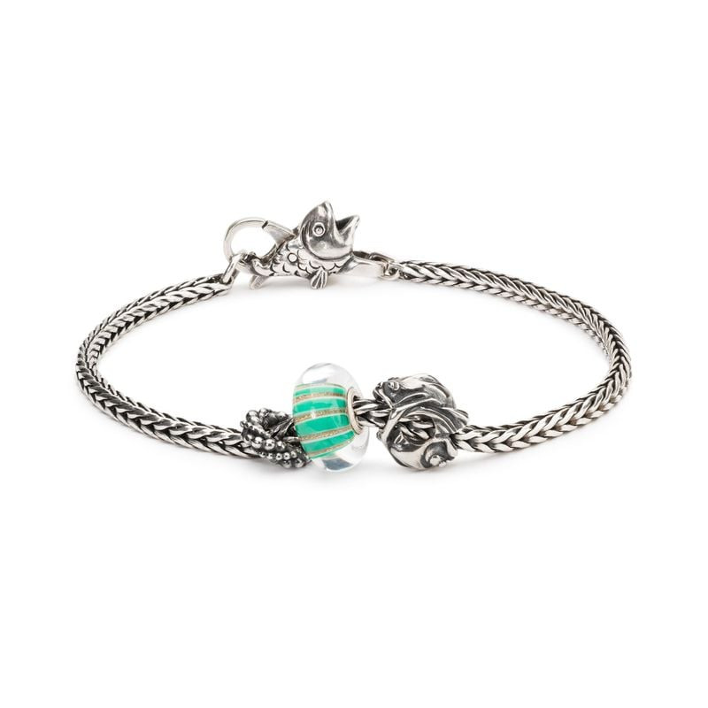 Perle TROLLBEADS Rayon scintillant présentée sur un bracelet en argent avec une breloque poisson.