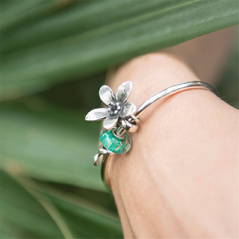 Image lifestyle : perle TROLLBEADS Rayon scintillant au poignet d'une personne avec une breloque fle