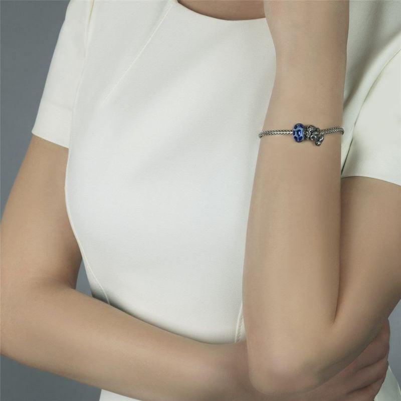 Femme en haut blanc avec un bracelet à chaîne en argent et la perle Trollbeads Guépard de saphir ble