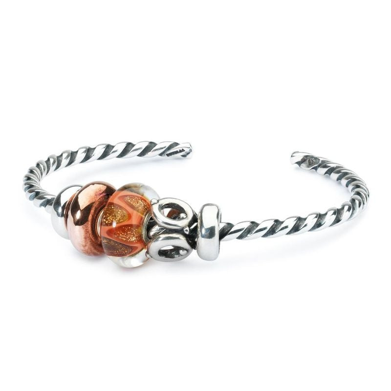 Perle Trollbeads Rires et amour Verre Doré exposée dans une ambiance chaleureuse et dorée.