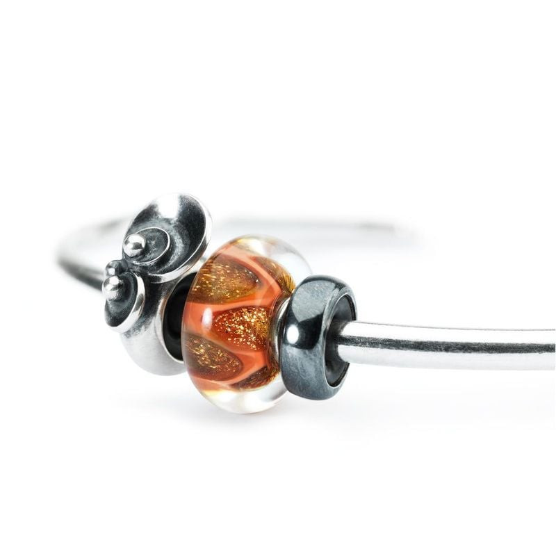 Perle Trollbeads Rires et amour Verre Doré dans une ambiance chaleureuse, orange et dorée
