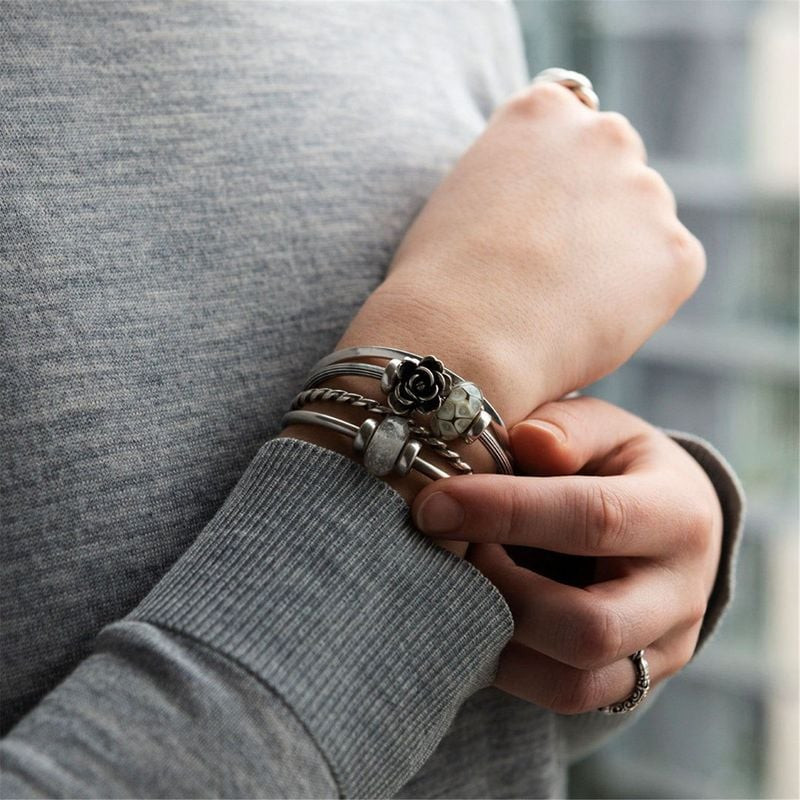 Femme portant des bracelets Trollbeads superposés avec la perle en verre Essence de l'Union et des c