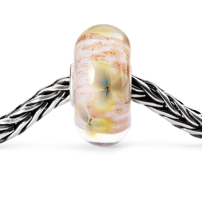 Perle de Verre Trollbeads Fleurs Sauvages Verre Rose sur fond floral, image d'ambiance naturelle et 