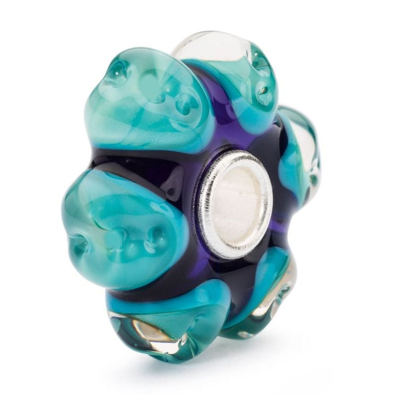 Gros plan sur la perle Trollbeads Rêverie en verre Murano, pétales turquoise, cœur violet profond et