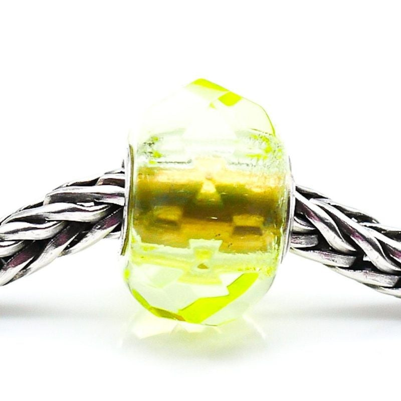 Gros plan de la perle Trollbeads Prisme Vert sur un bracelet en argent, son verre vert lumineux sous