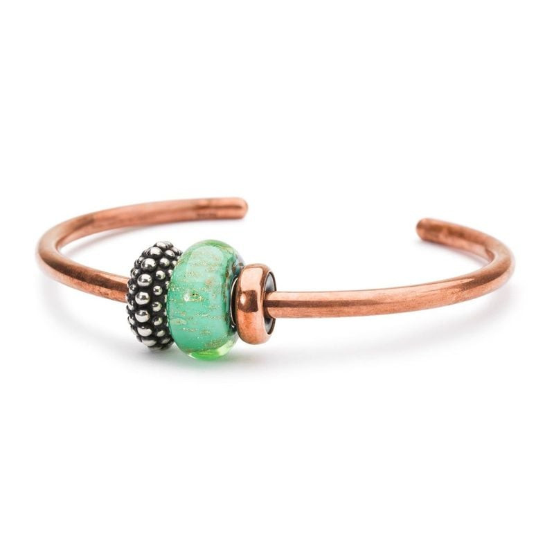 Perle Trollbeads Fonds marins en verre vert présentée sur un bracelet jonc en cuivre avec des charms