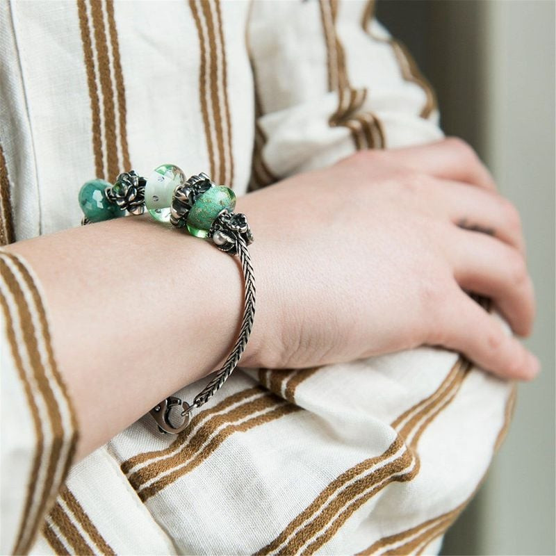 Femme portant un bracelet Trollbeads avec la perle Fonds marins en verre vert au poignet