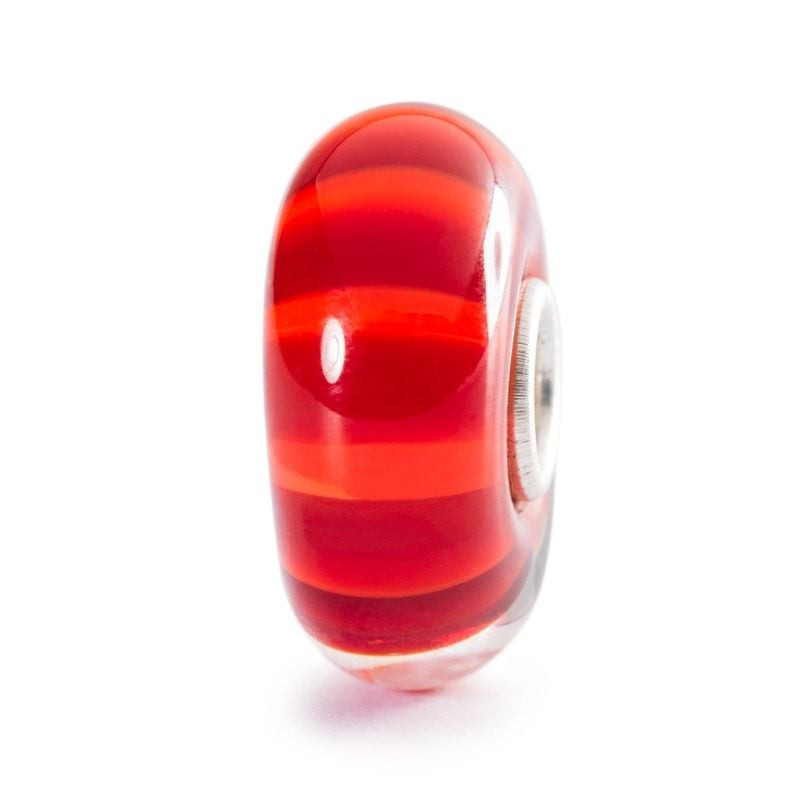 Perle Trollbeads Rayons d'automne en verre à rayures rouges et orange sur fond blanc, vue de côté