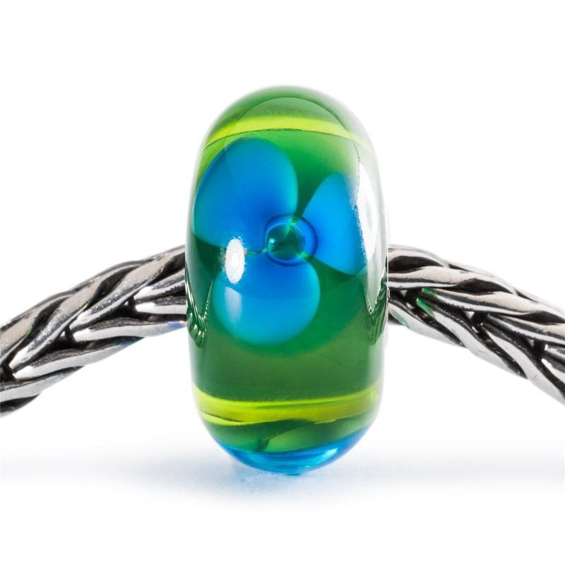 Breloque en verre Trollbeads Fleurs de ruisseau enfilée sur un bracelet tressé en argent, montrant t