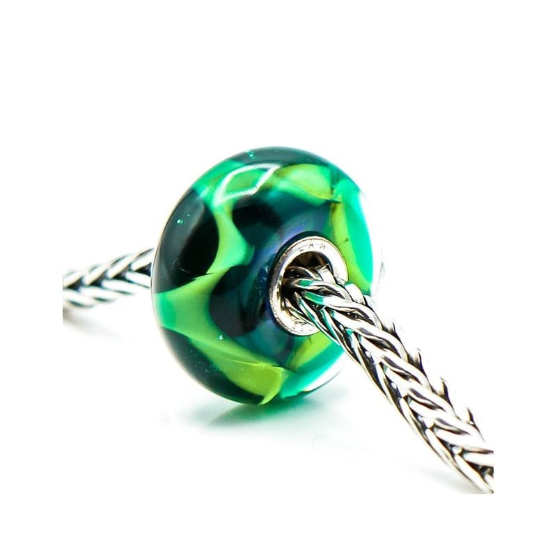 Perle Trollbeads Vague Verte Verre Vert en verre soufflé, posée dans une ambiance marine aux reflets