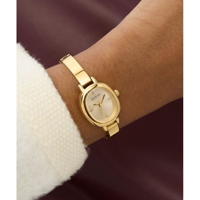 Montre Analogique GUESS Collection Penelope Bracelet acier doré au poignet d'une femme élégante