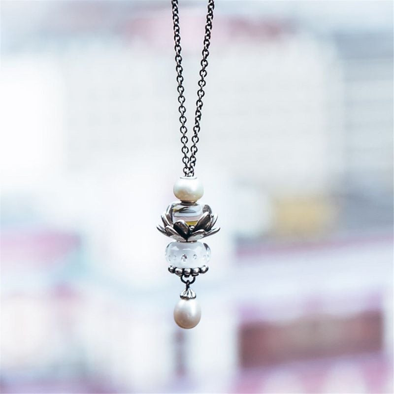 Perle Trollbeads Diamant-like blanc suspendue à une chaîne en argent avec des perles et un pendentif