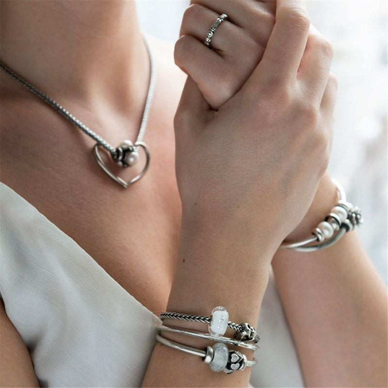 Femme portant la perle Trollbeads en verre blanc sur un bracelet en argent avec perles et cœurs
