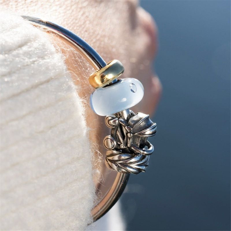 Perle Trollbeads Petit garçon en verre bleu clair sur un bracelet doré avec des charms en argent, po