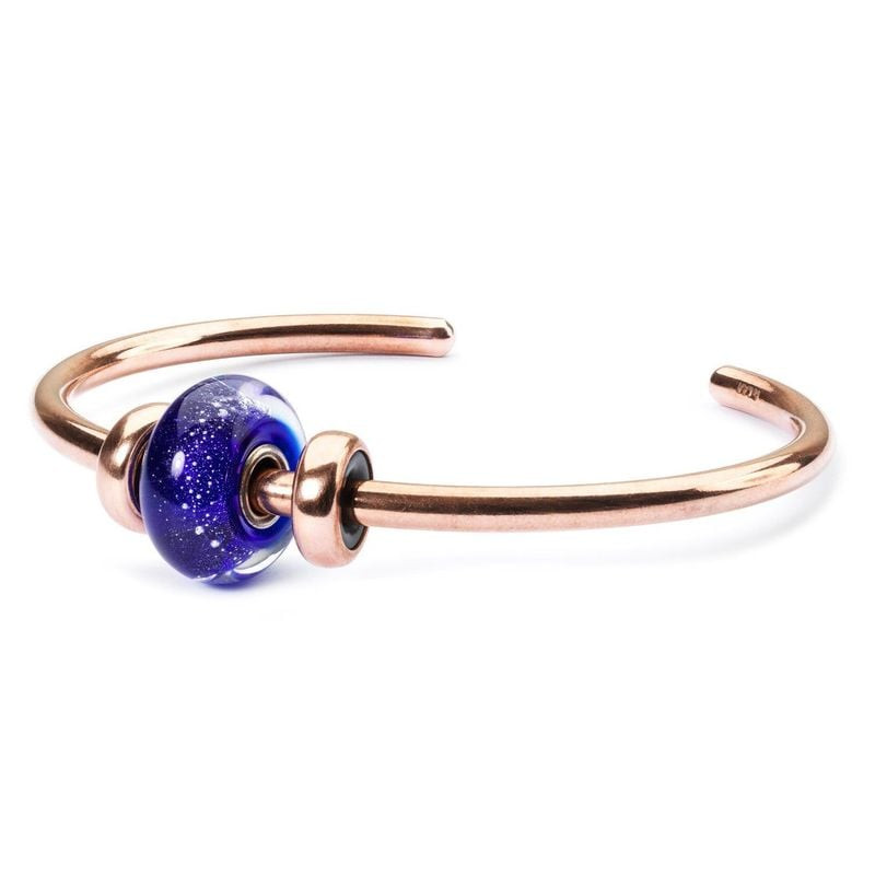 Jonc Trollbeads en cuivre avec une perle en verre bleue et deux stoppeurs en cuivre sur fond blanc