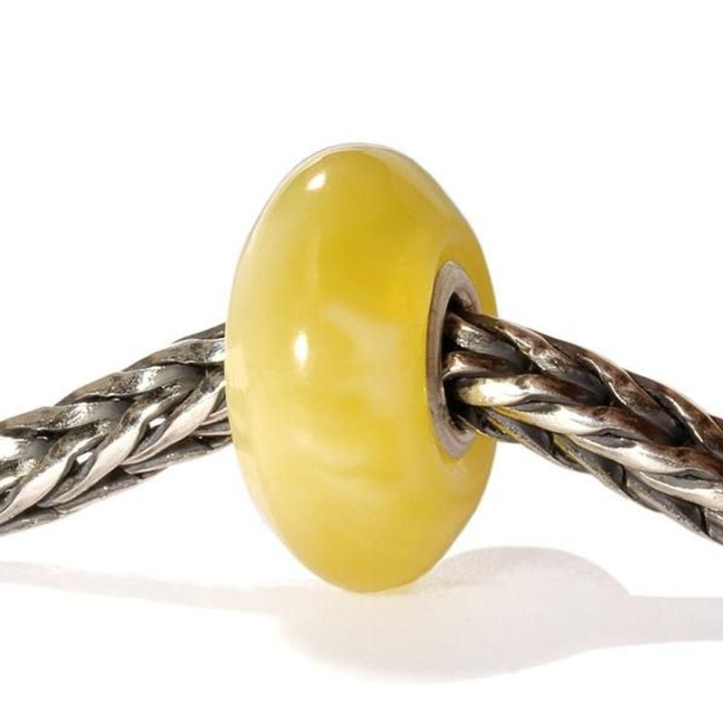 Perle de charme Trollbeads Albâtre en verre jaune enfilée sur un bracelet en argent tressé avec une 