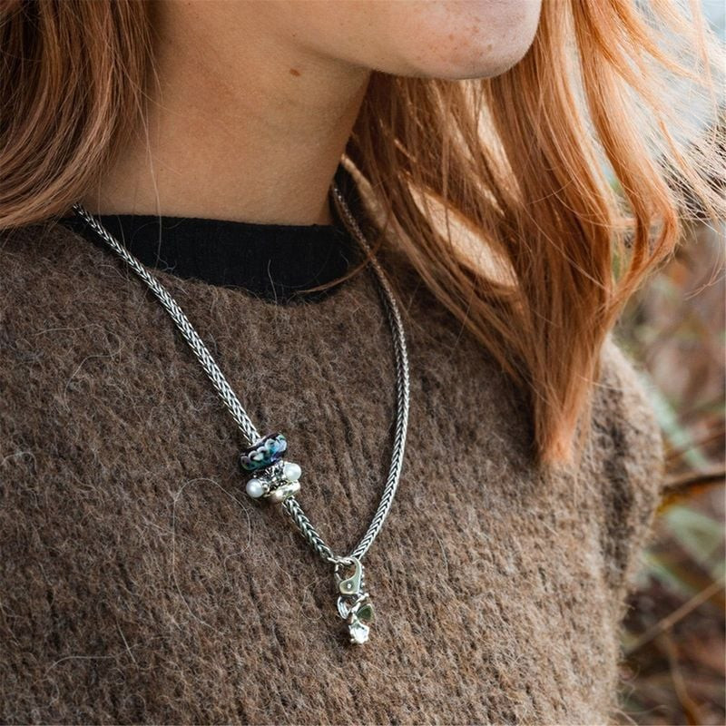 Femme aux cheveux roux portant le pendentif Trollbeads Fleur d'Automne sur une chaîne en argent tres