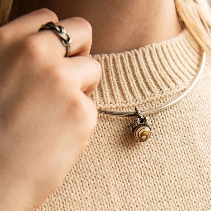 Femme portant le pendentif Trollbeads Château de Sable sur un collier argenté, avec un pull en maill